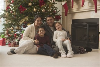 Family sitting on floor of living room on Christmas morning