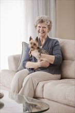 Caucasian woman sitting on sofa holding dog