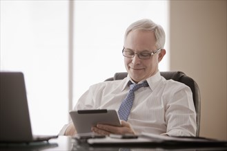 Caucasian businessman using digital tablet at desk