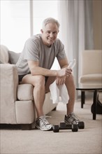 Caucasian man in living room drinking water after exercise
