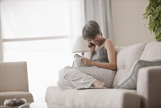 Mixed race woman on sofa talking on cell phone