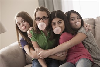 Friends sitting on sofa chewing bubble gum