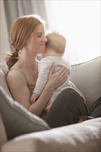 Caucasian mother sitting on sofa holding son