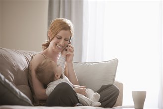 Caucasian mother holding son and talking on cell phone