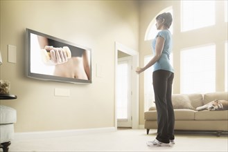 Mixed race woman watching exercise program on television