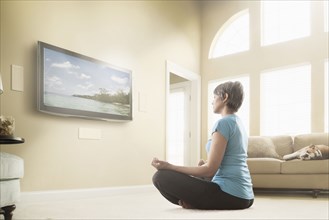 Mixed race woman watching meditation program on television