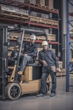 African American workers with forklift in factory