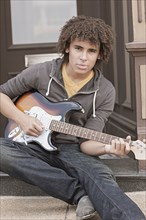 Mixed race teenager playing electric guitar