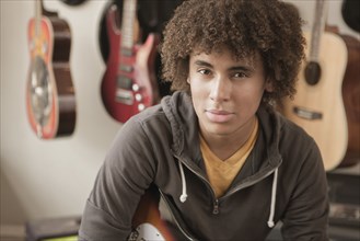 Mixed race teenager sitting with guitars