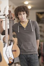 Mixed race teenager standing with guitars in music store