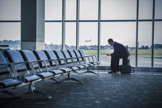 Caucasian businessman sitting suitcase in airport