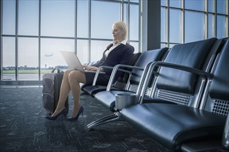 Caucasian businesswoman using laptop in airport
