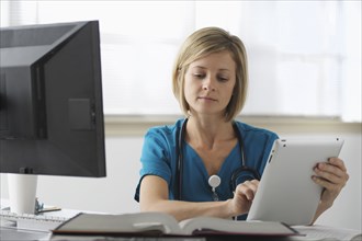 Caucasian surgeon reading books and using digital tablet