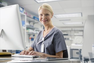 Caucasian nurse working at computer in hospital