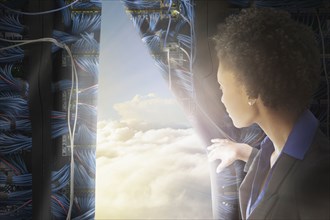 African American businesswoman pulling back curtain to clouds
