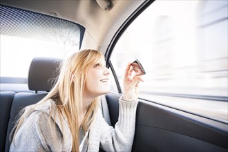 Woman taking pictures out car window