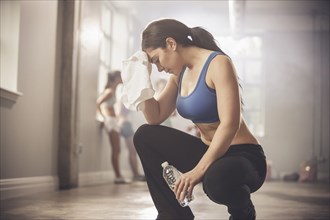Woman wiping sweat with towel in gym