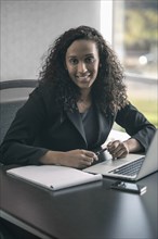 Mixed race businesswoman smiling at desk