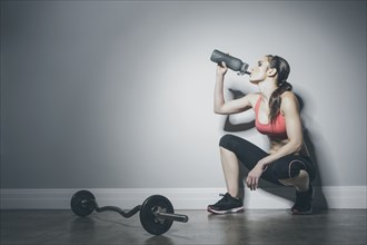 Caucasian woman in sportswear drinking from water bottle