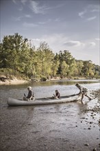 Three generations of Caucasian men in canoe on river