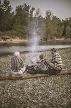 Three generations of Caucasian men relaxing near campfire