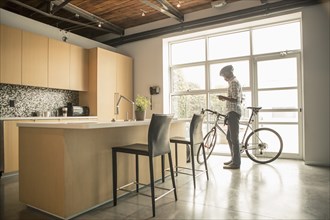 Black businessman with bicycle using cell phone in office kitchen