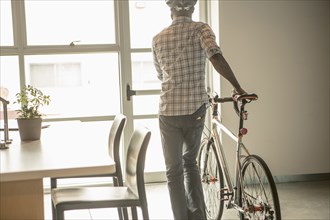 Black businessman leaving office with bicycle