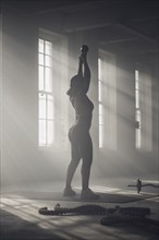 Black woman lifting weights in dark gym