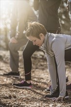 Runners stretching on dirt ground