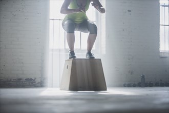Athlete crouching on platform in gym