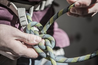 Athlete tying knot on climbing harness