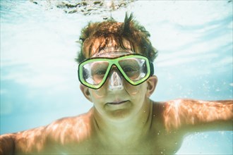 Caucasian boy swimming underwater in swimming pool