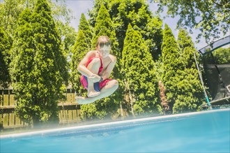 Caucasian boy jumping into swimming pool