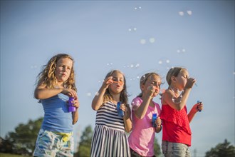 Girls blowing bubbles outdoors