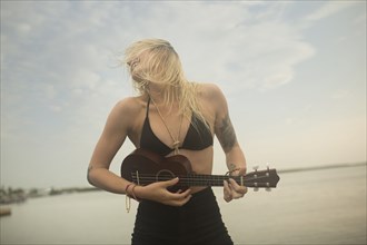 Caucasian woman playing ukulele on beach