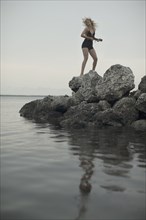 Caucasian woman standing on rocks by remote lake