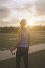 Mixed race athlete holding water bottle on sports field