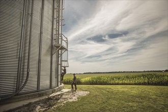 Caucasian farmer and son climbing grain silo