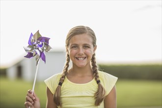 Caucasian girl holding pinwheel on farm