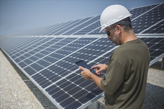 Caucasian technician using digital tablet near solar panels