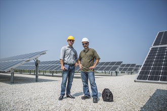 Caucasian technicians standing near solar panels