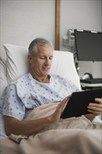 Caucasian man using digital tablet in hospital room
