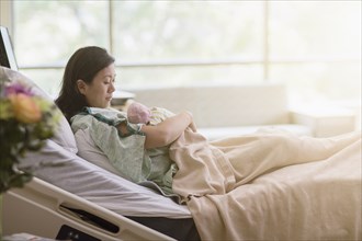 Mother cradling newborn baby in hospital room