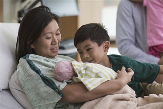 Family admiring newborn baby in hospital room