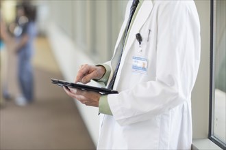 Doctor using digital tablet in hallway
