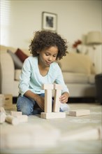 Mixed race girl playing with building blocks