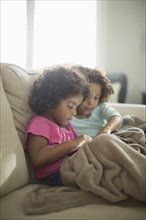 Sisters using digital tablet on sofa