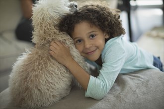 Mixed race girl hugging dog