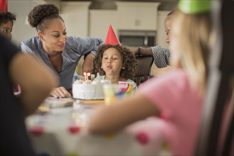 Girl blowing birthday candles at party