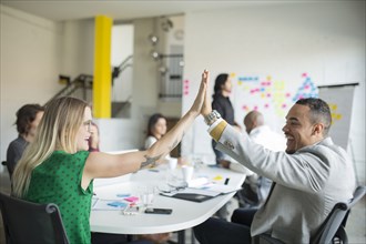 Business people high-fiving in office meeting